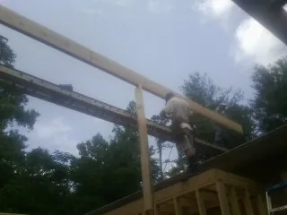 Carpenter setting a ridge beam over a new addition frame — Ice Dam Removal by Roofing Brothers in De Witt