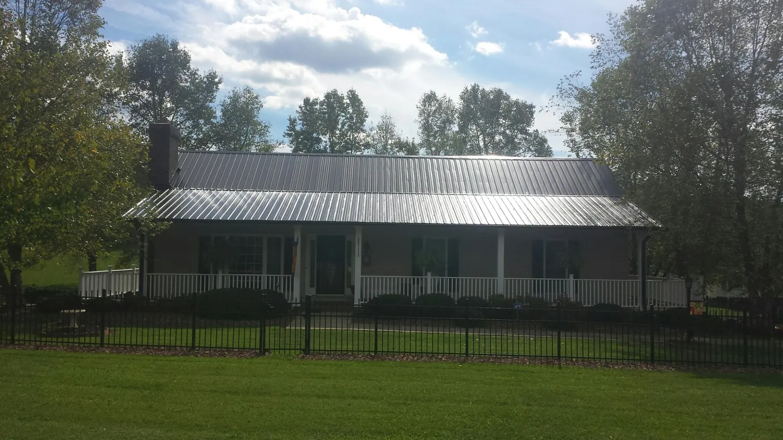 Gray metal roof on a brick ranch with a full width front porch — Gutter Guard Installation work by our crew in De Witt