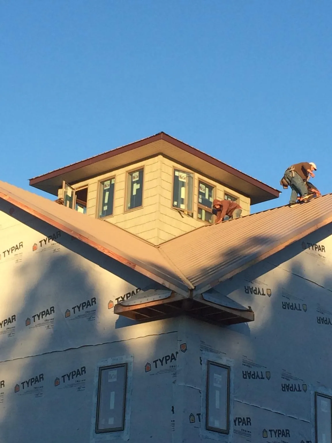 Roofers working around a rooftop cupola on a new metal roof at sunset — Roof Waterproofing in De Witt by Roofing Brothers